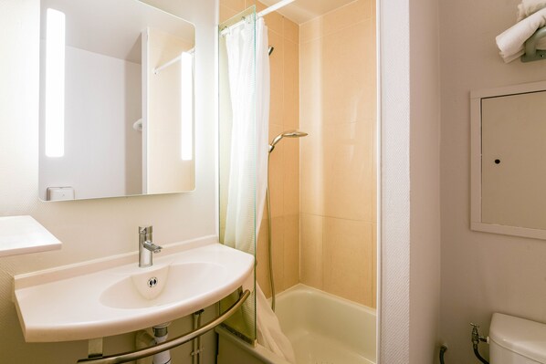 Un baño con lavamanos, espejo, ducha e inodoro.