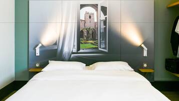 A hotel room with a large bed, two bedside tables, and a wall-mounted light fixture.