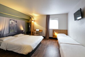 Habitación de hotel con dos camas, un escritorio, una silla, un televisor y una ventana con cortinas.