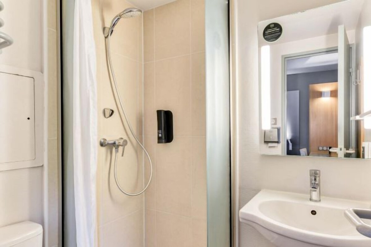 Un baño moderno con ducha, lavamanos y espejo.