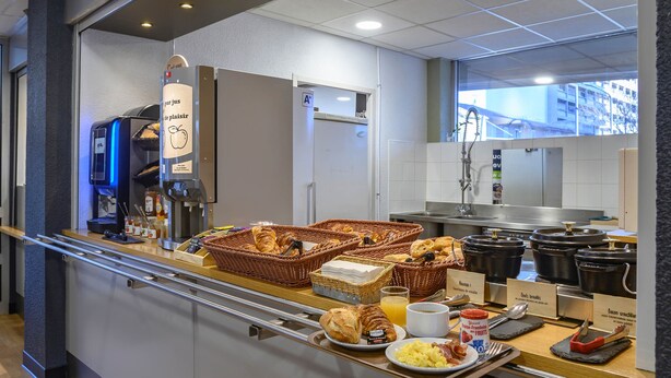 Un bufé de desayuno con diversos alimentos, cestas y una máquina de café.