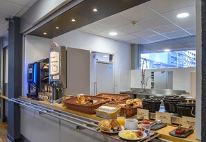 Un buffet de petit-déjeuner proposant une variété d’aliments, des paniers et une machine à café.