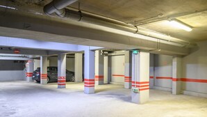 Un aparcamiento subterráneo con pilares de hormigón, un coche y una motocicleta.
