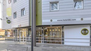 Un hotel B&B con fachada de vidrio, una recepción visible y una dirección web.