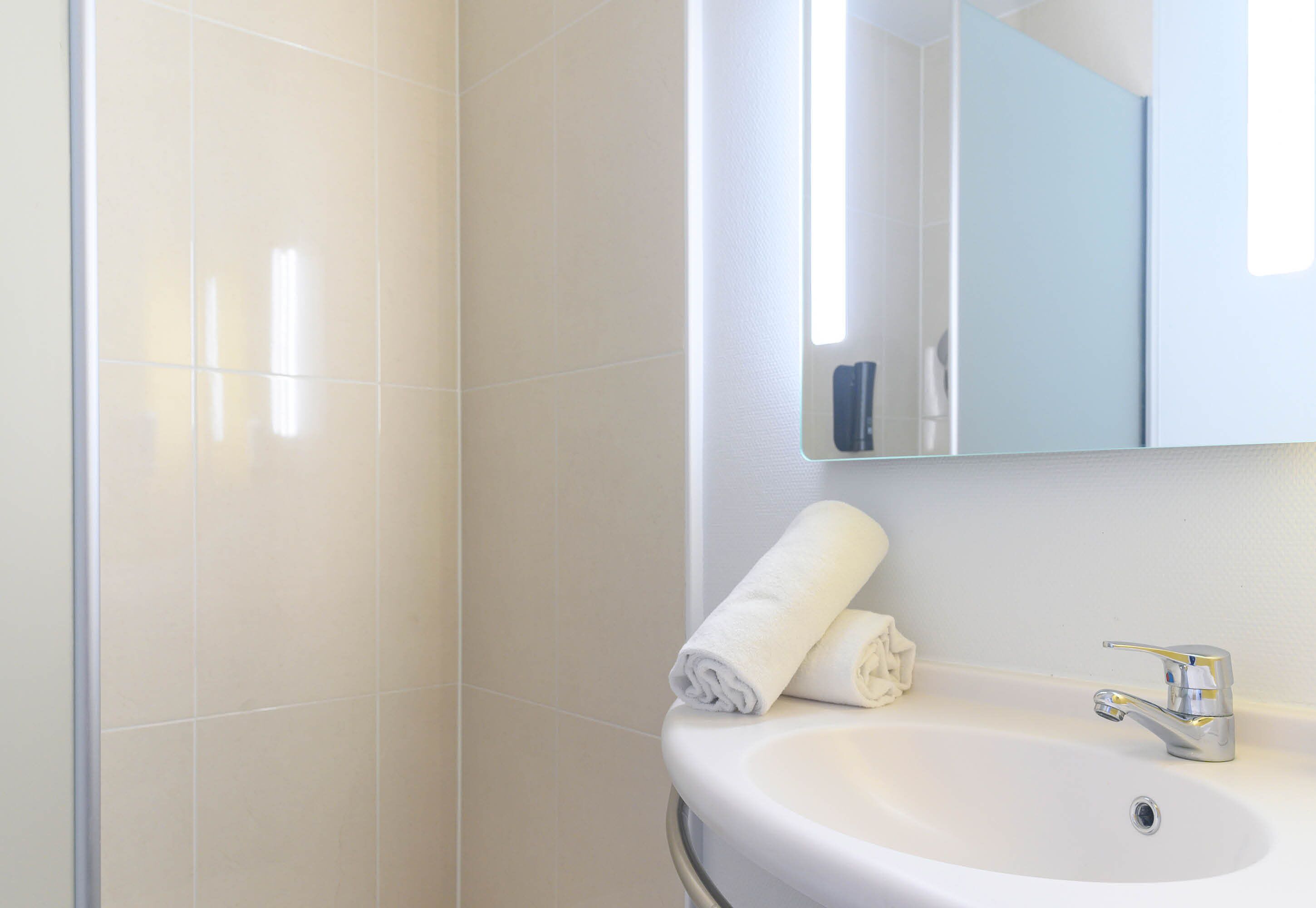 Un baño con un lavamanos blanco, un espejo y una toalla.