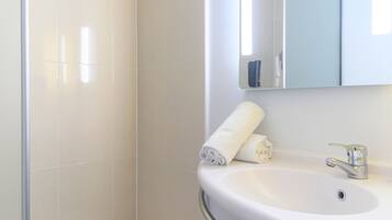 A bathroom with a white sink, a mirror, and a towel.