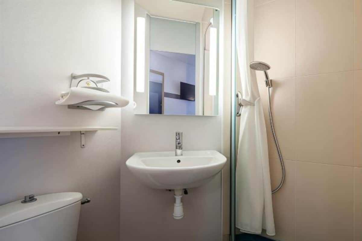 Un baño con un lavamanos blanco, un inodoro, una ducha y un espejo.