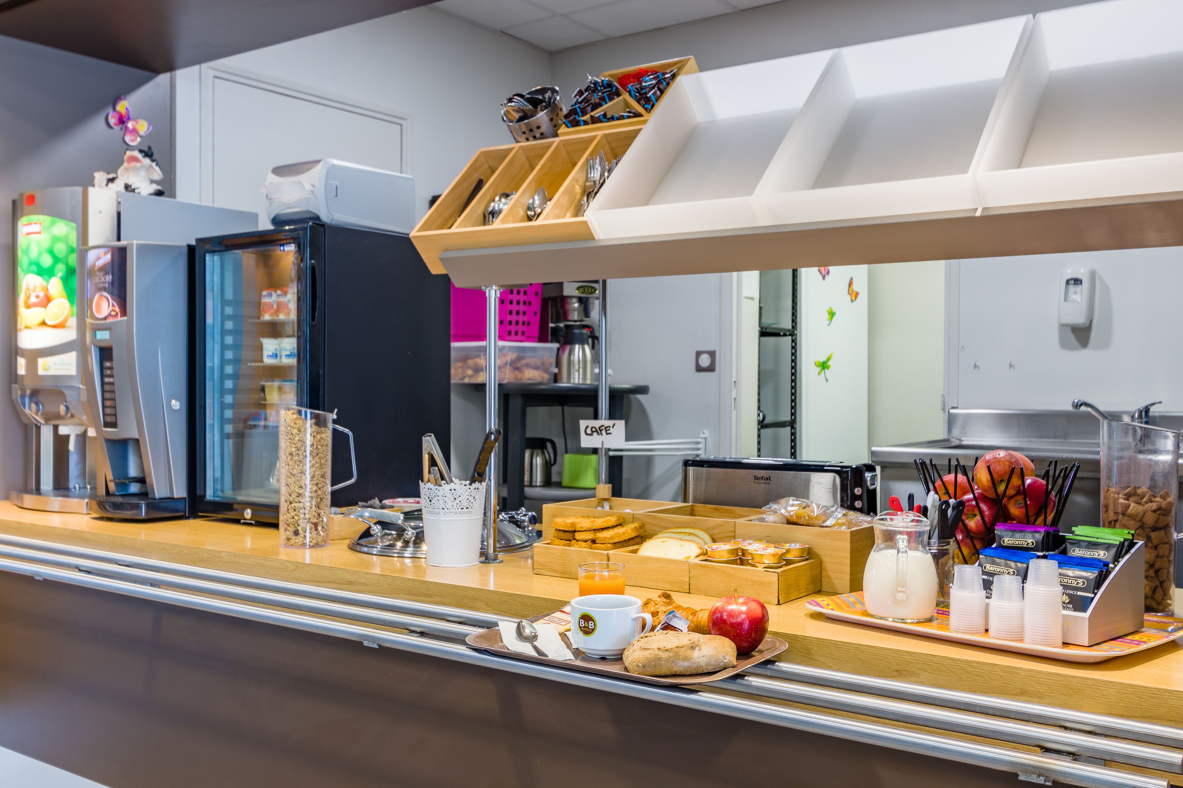 A breakfast buffet with various food items, a coffee machine, and a juice dispenser.