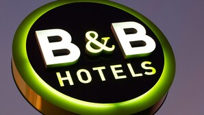 Een rond bord met de tekst 'B&B HOTELS' voor een schemerlucht.