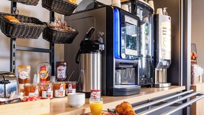 A breakfast buffet with various food items, a coffee machine, and a juice dispenser. - B&B HOTEL Valence Sud (Valence)