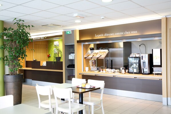 A modern cafe with a reception desk, seating area, and a counter with coffee machines. - B&B HOTEL Perpignan Sud Marché International (Perpignan)