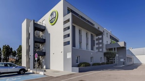 A modern hotel with a prominent B&B logo, a parking area, and a clear blue sky. - B&B HOTEL Perpignan Sud Marché International (Perpignan)