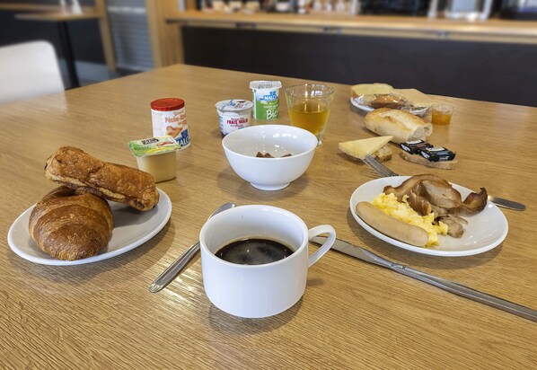 A table with food items including croissants, a cup of coffee, and a plate with scrambled eggs and mushrooms.