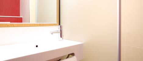 A bathroom with a white sink, a mirror, and a towel hanging on the wall.