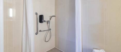 A shower area with a handheld showerhead, a towel rack, and a shower curtain.