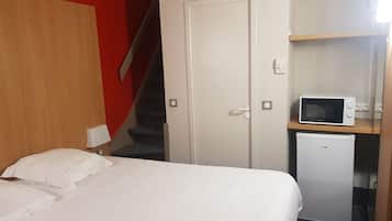 Une chambre avec un lit, un four à micro-ondes et un réfrigérateur.