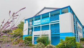 Een modern gebouw met een blauw-wit kleurenschema, met de tekst 'Kyriad DIRECT'.