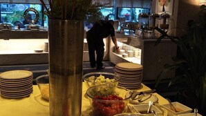 Een buffetopstelling met diverse gerechten en een persoon op de achtergrond.