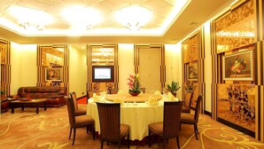 A hotel dining room with a round table set for six, surrounded by chairs, and a television on the wall. - Shenzhen Lido Hotel (Shenzhen)