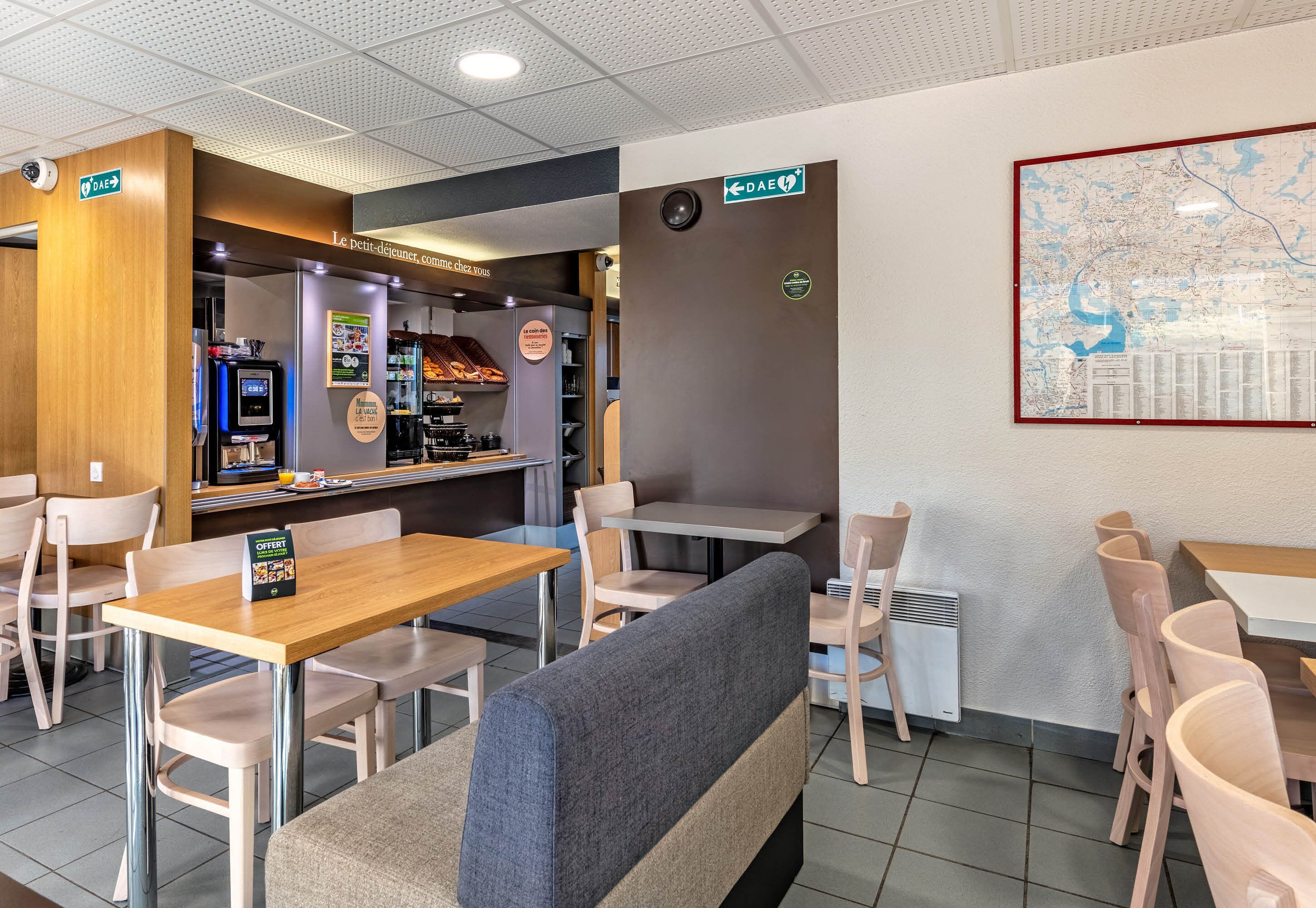 Un restaurante con cabinas, mesas y una pantalla mostrando el menú.