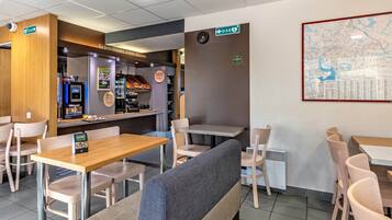 Un restaurante con cabinas, mesas y una pantalla mostrando el menú.