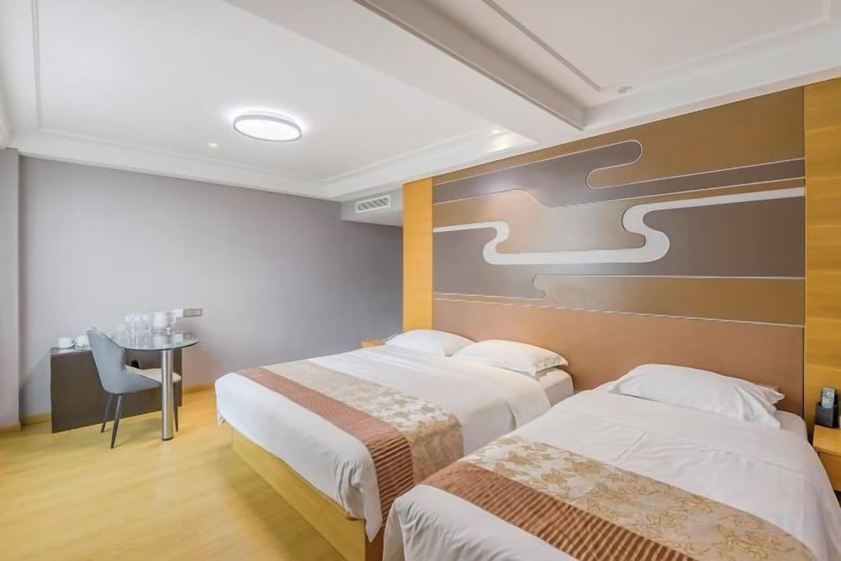 A hotel room with two beds, a desk, and a chair.