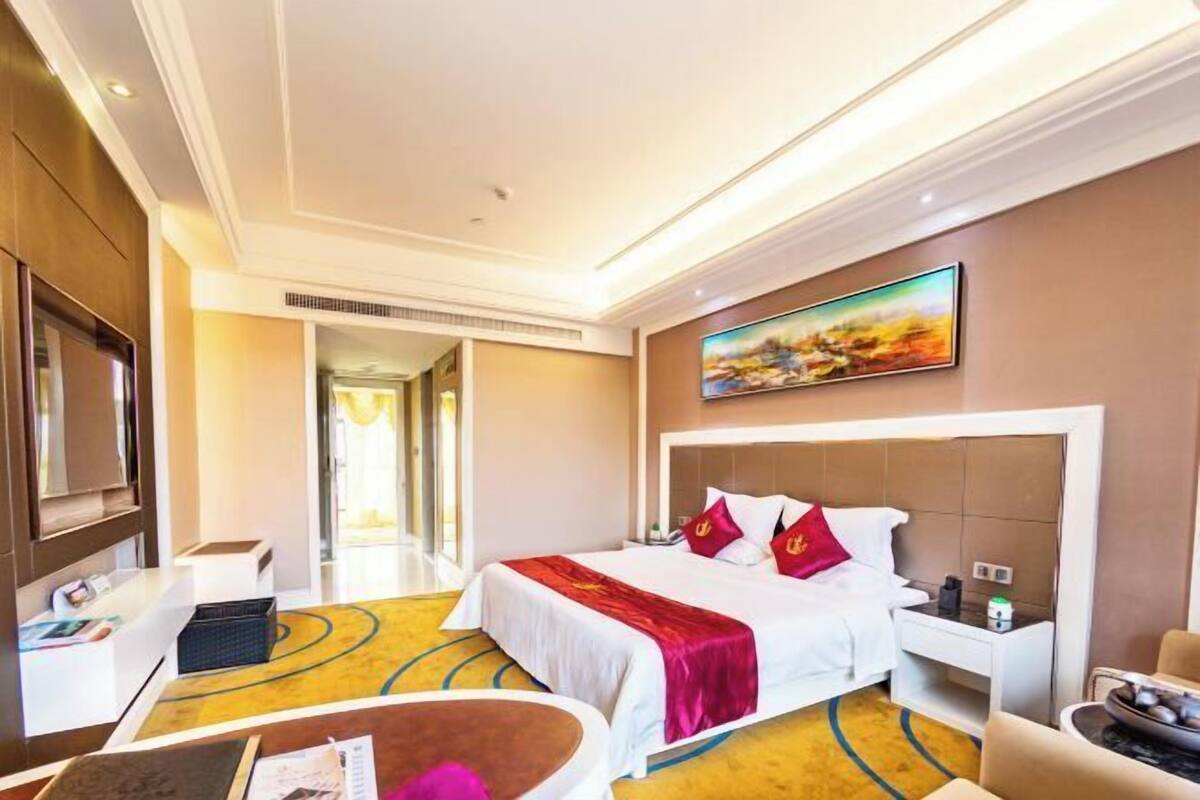 Een hotelkamer met een bed, een bureau, een stoel en een schilderij aan de muur.