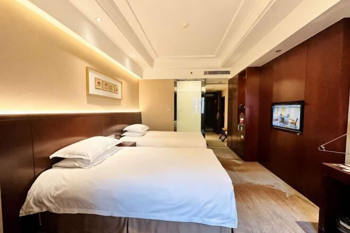 Une chambre d’hôtel avec deux lits, une télévision et un tableau encadré au mur.
