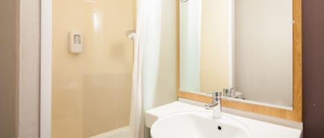 Un baño con un lavamanos blanco, un espejo y una ducha.