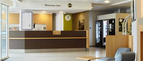 A reception area with a wooden reception desk, a clock, and a seating area with a table and chairs.