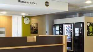 Een receptiebalie met een klok, automaten en een bord waarop staat 'Bienvenue chez B&B'.