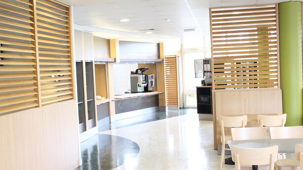 Een modern interieur met houten paneelwanden, een receptiebalie en een zithoek met tafels en stoelen.