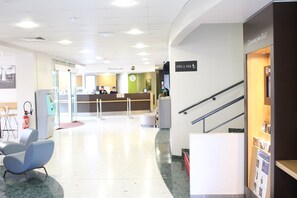 A reception area with a counter, a clock, and a fire extinguisher. - B&B HOTEL Paris Roissy CDG Aéroport (Roissy-en-France)