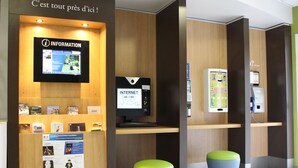 Een receptie met een computerterminal, een bordje met de tekst 'INFORMATIE' en een zithoek met krukken.