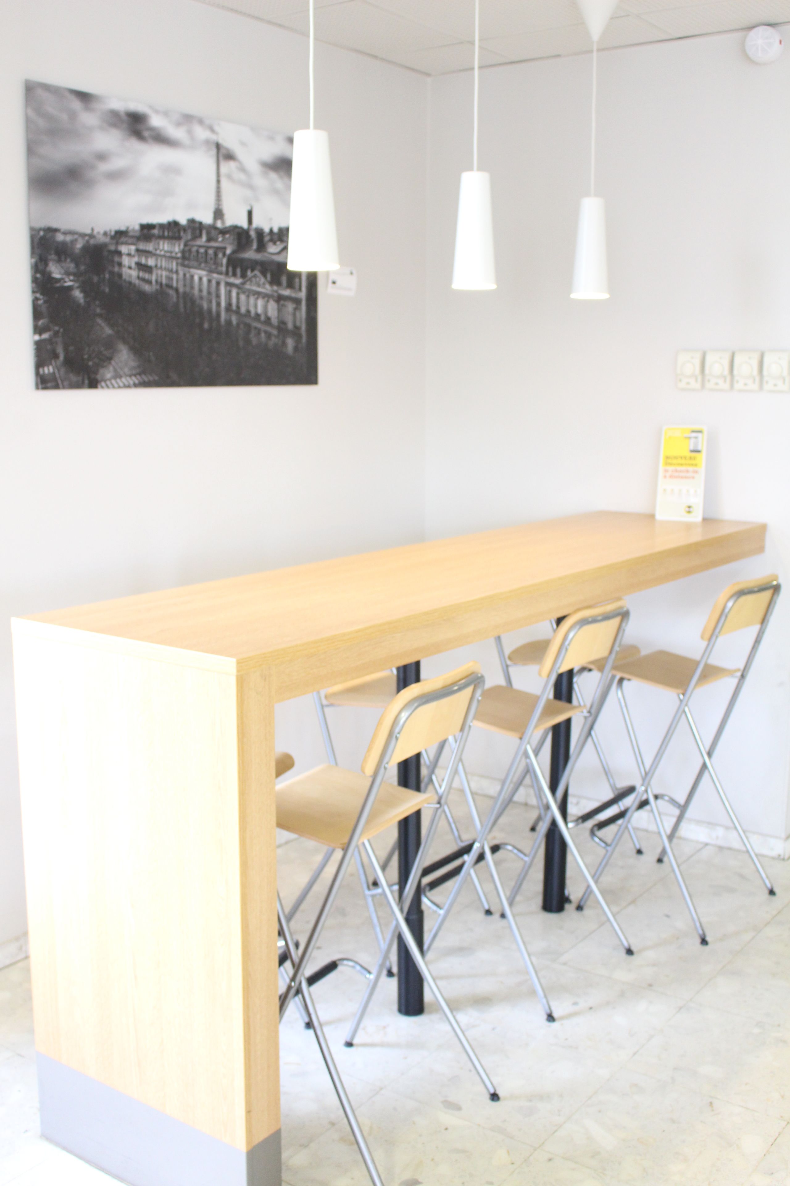 A modern bar area with a wooden counter, four foldable chairs, and pendant lights.