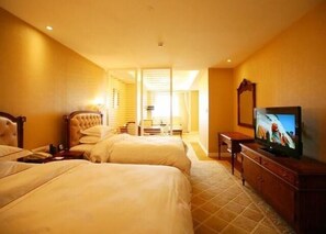 A hotel room with two beds, a television, and a desk.