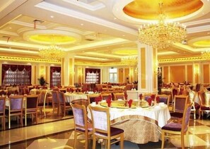 A large banquet hall with round tables, chandeliers, and a polished floor.