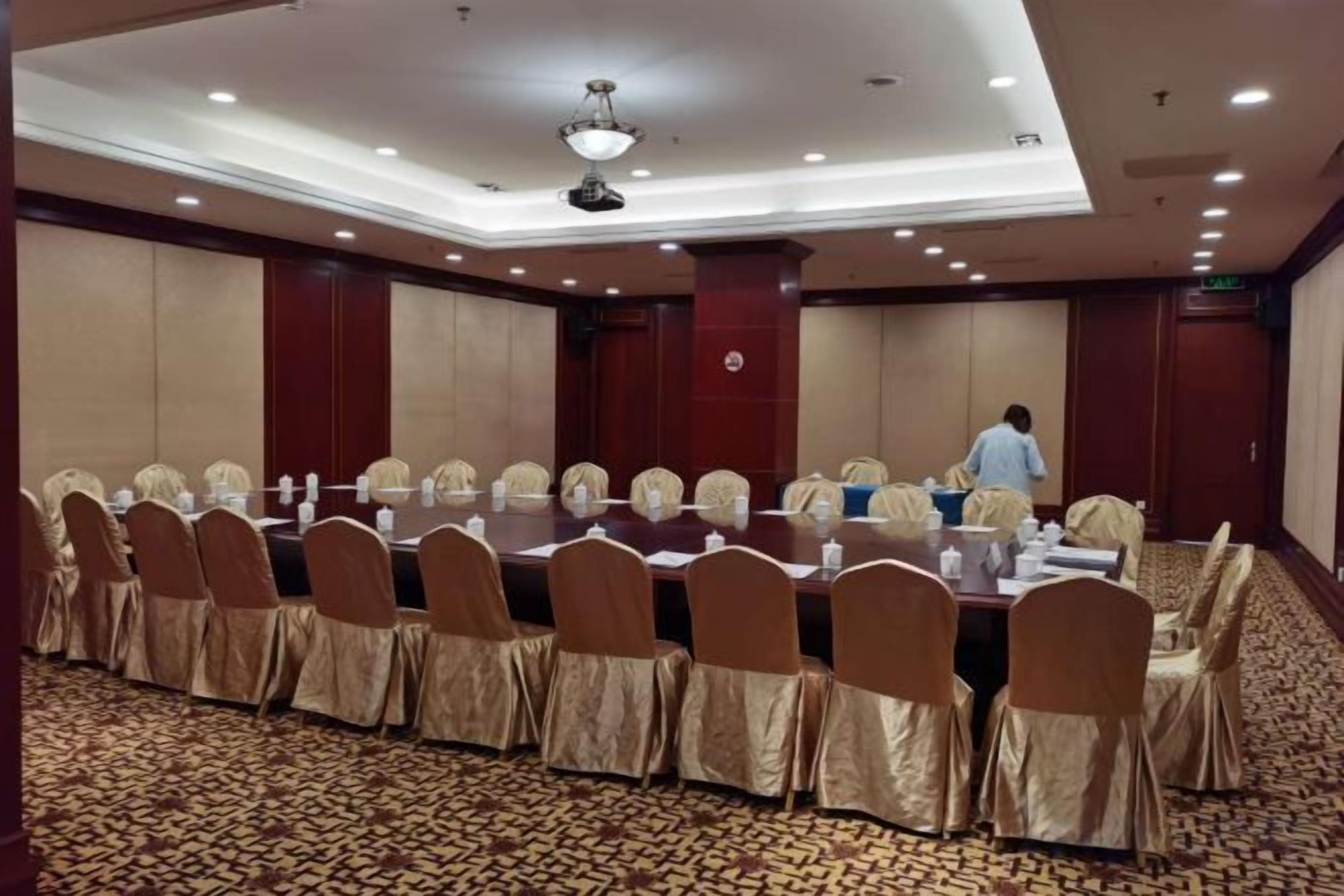 A conference room with a long table, chairs, and a carpeted floor.