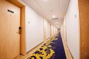 A hotel hallway with wooden doors, a blue carpet with a gold pattern, and a sign indicating room number 2018. - Chunlan Business Hotel (Taizhou)