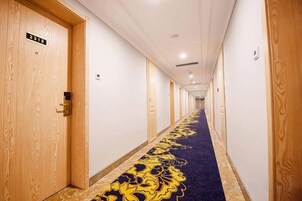 A hotel hallway with wooden doors, a blue carpet with a gold pattern, and a sign indicating room number 2018.