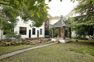 A traditional-style building with a courtyard, a gazebo, and a stone pathway.