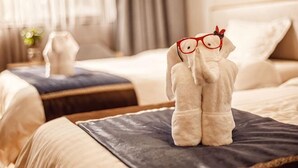 A hotel room with a bed, a nightstand, and a decorative item on the bed. - Chunlan Business Hotel (Taizhou)