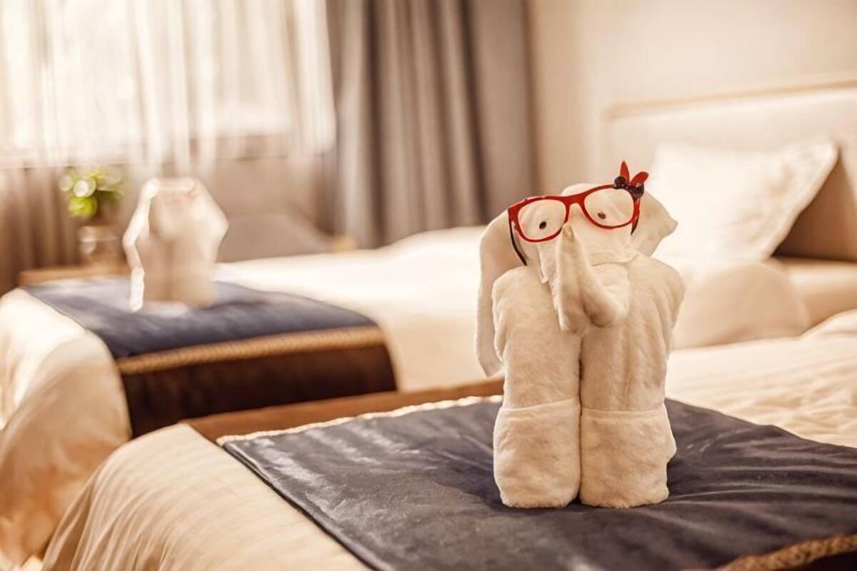 A hotel room with a bed, a nightstand, and a decorative item on the bed.
