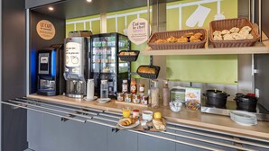 Un comptoir où l’on sert le petit-déjeuner, avec des machines à café, une variété d’aliments pour le petit-déjeuner et un panneau sur lequel on peut lire : « Pour le petit-déjeuner, c’est à vous de choisir. »