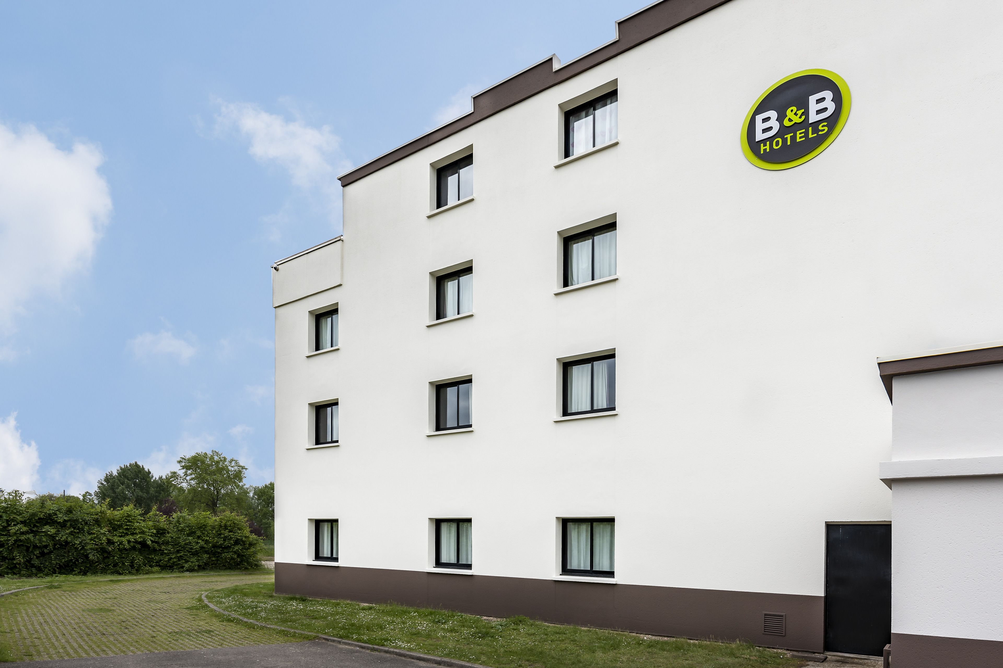 A modern hotel building with a white facade, multiple windows, and a B&B Hotels logo.