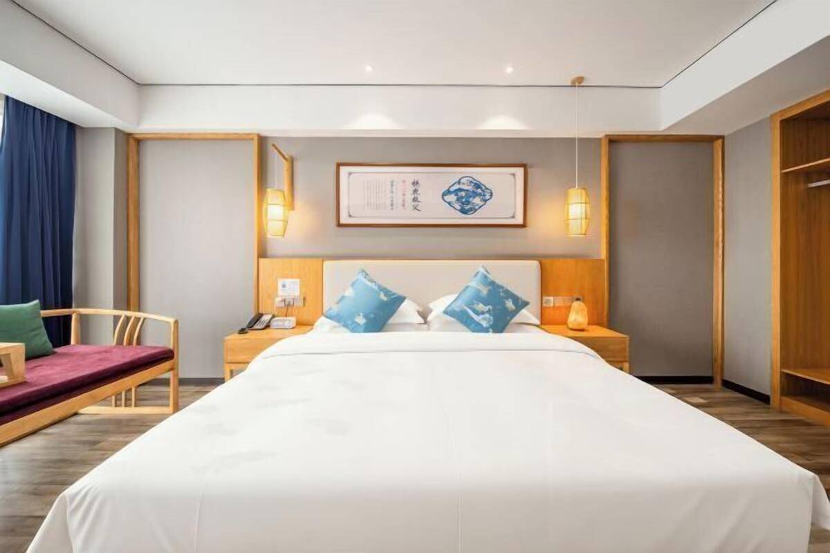 Een hotelkamer met een groot bed, nachtkastjes, een stoel en een kledingkast.