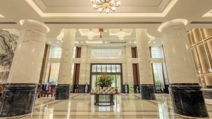 A spacious lobby with marble columns, a chandelier, and a central floral arrangement. - Wulan Hot Spring Hotel (Haikou)