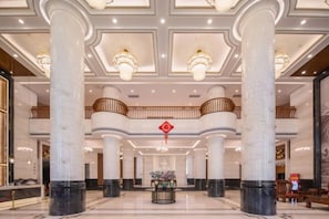 A grand lobby with marble columns, a central floral arrangement, and a red decorative element on the ceiling. - Wulan Hot Spring Hotel (Haikou)