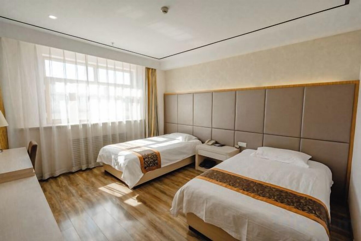 A hotel room with two beds, a desk, and a chair.