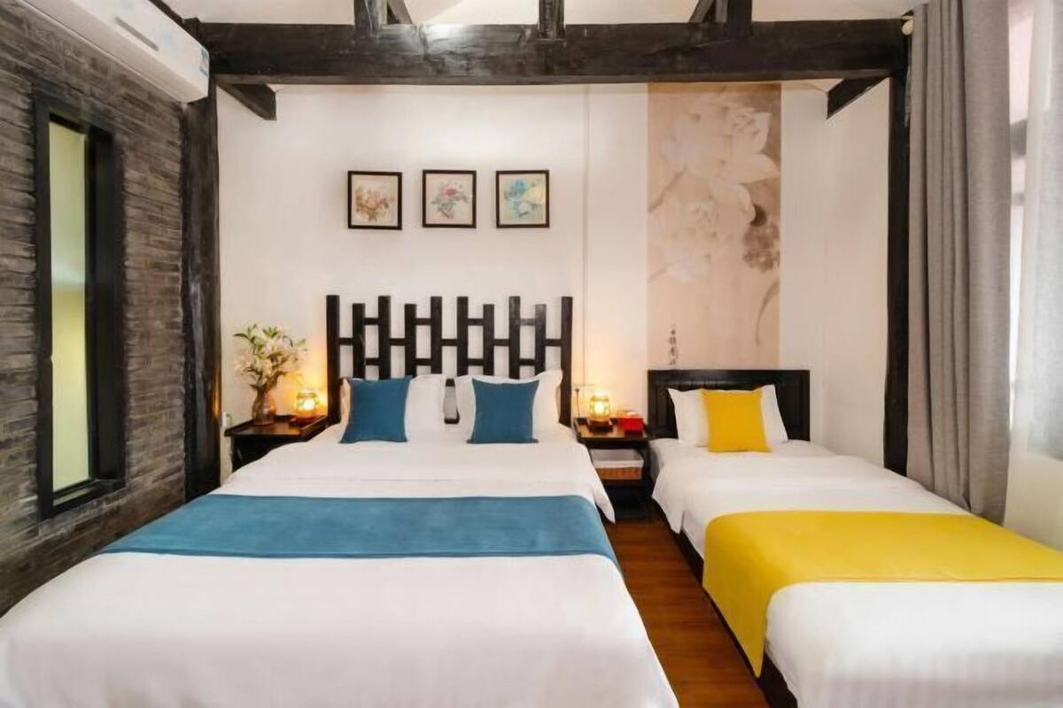 A hotel room with two beds, a wooden ceiling, and artwork on the wall.